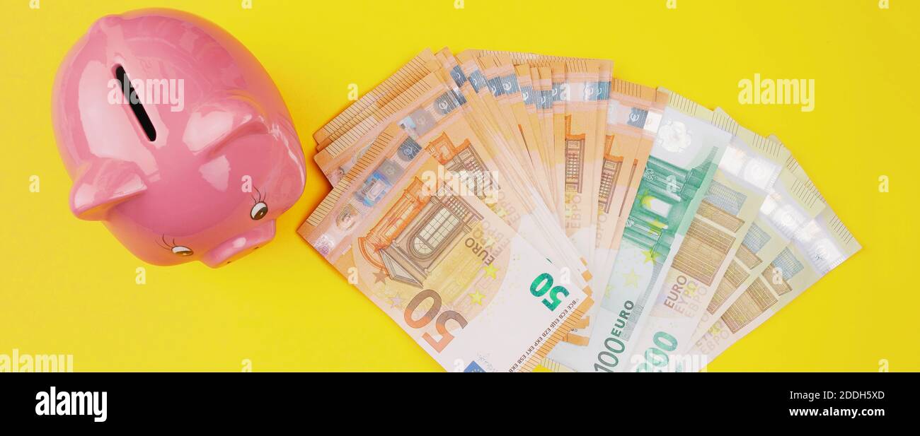 Draufsicht auf Stapel von Euro-Scheinen und Sparschwein auf gelbem Hintergrund, Geld sparen und Finanzierungskonzept Stockfoto