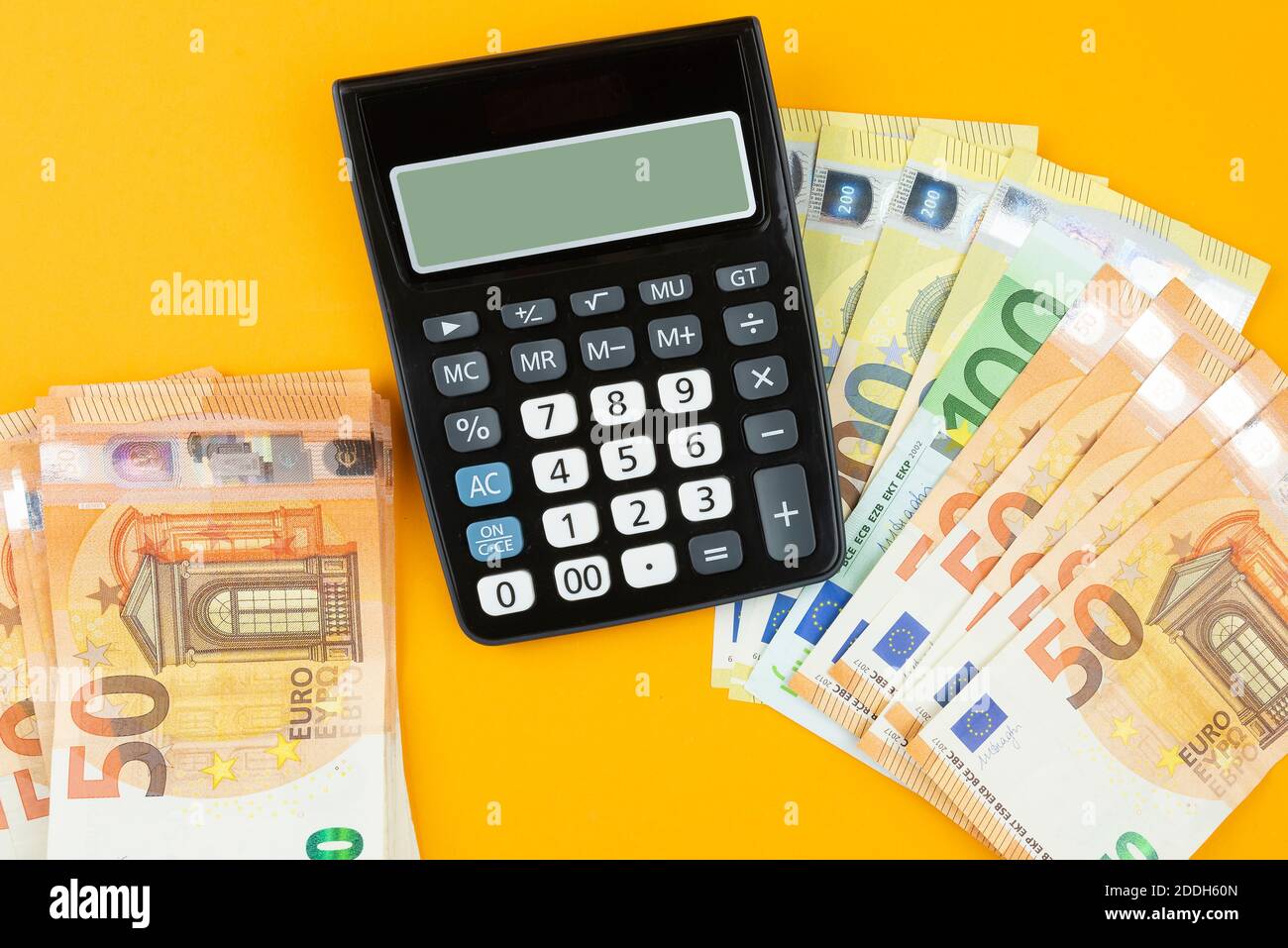 Oben Ansicht der Stapel von Euro-Rechnungen und Rechner auf orangefarbenem Hintergrund, sparen oder Geld ausgeben Konzept Stockfoto