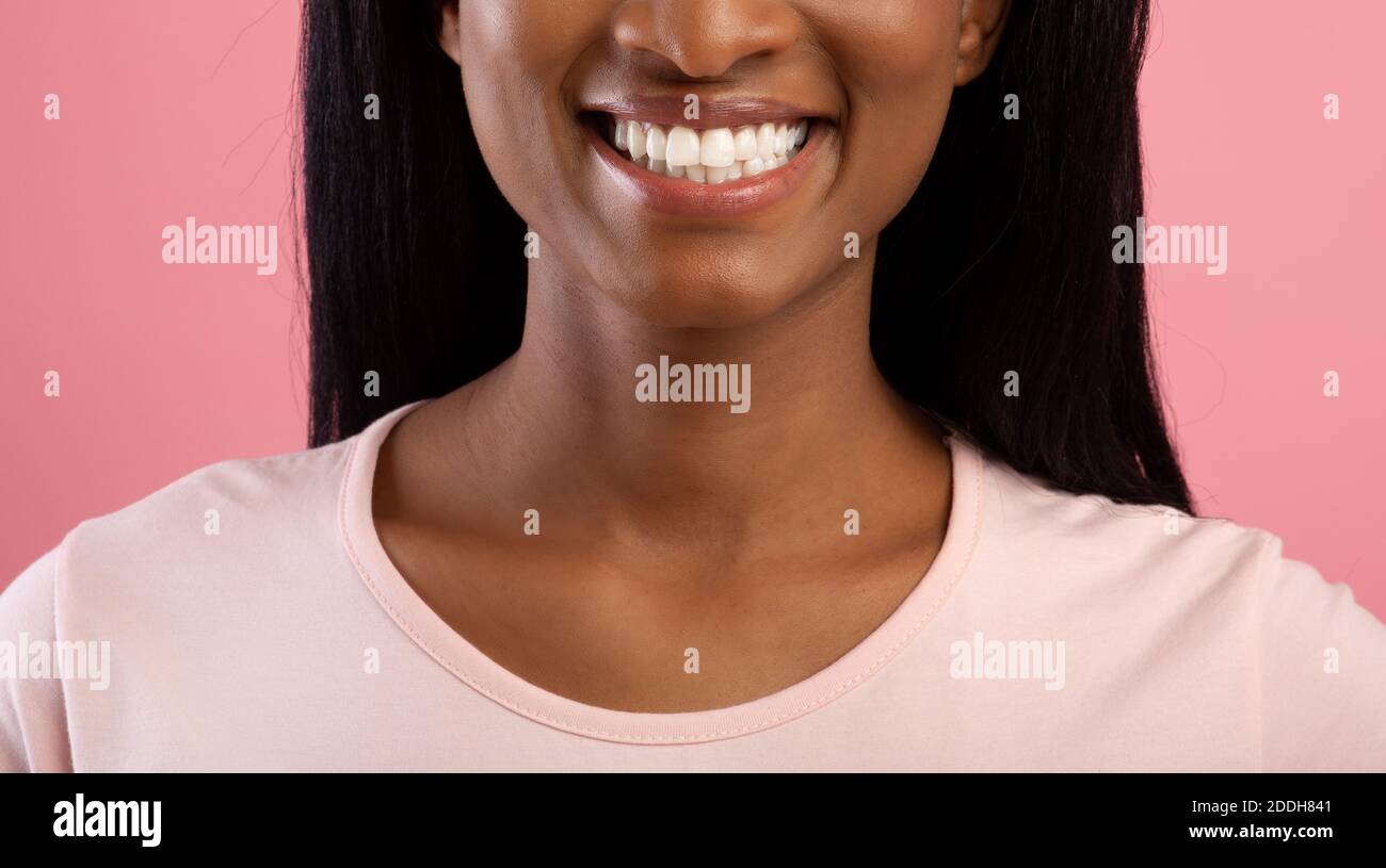 Zahnklinik. Beschnittene Ansicht der jungen schwarzen Dame mit schönen strahlenden Lächeln auf rosa Studio-Hintergrund, Banner-Design Stockfoto
