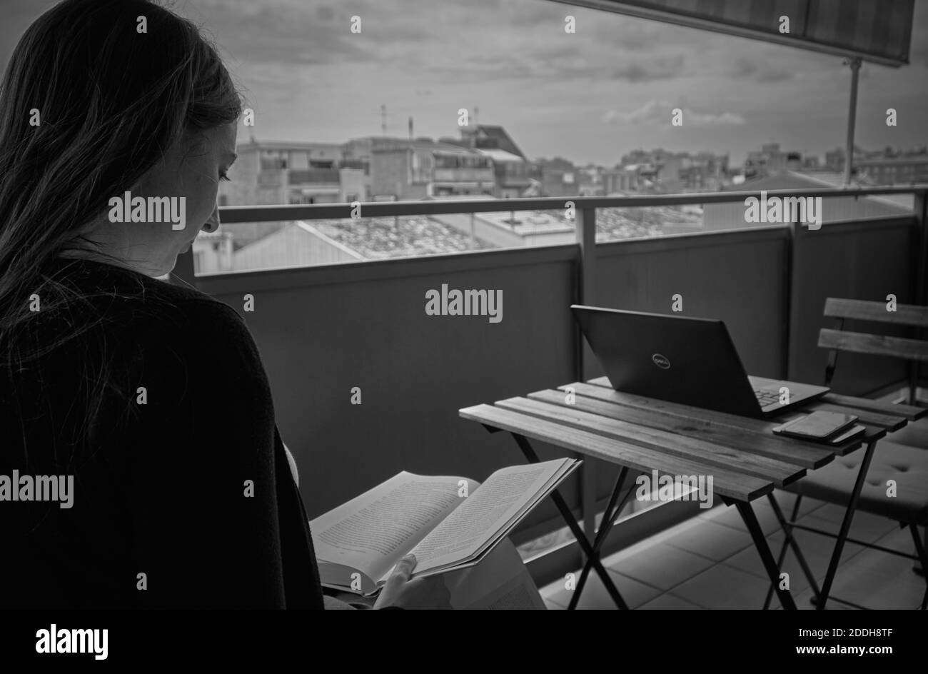 Frau beim Lesen auf dem Balkon während der Pandemie-Situation Stockfoto