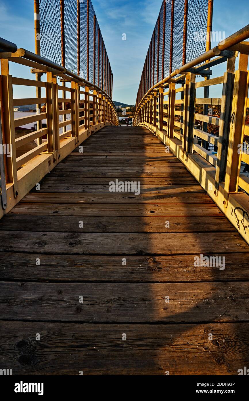 Perspektive einer Brücke mit Fokus auf den Holzboden Und Metallzaun bei Sonnenuntergang timek Stockfoto