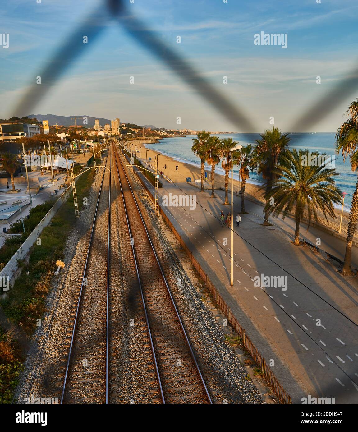 Eisenbahn und Badalona Strand durch das verblassen des Metalls Zaun Stockfoto