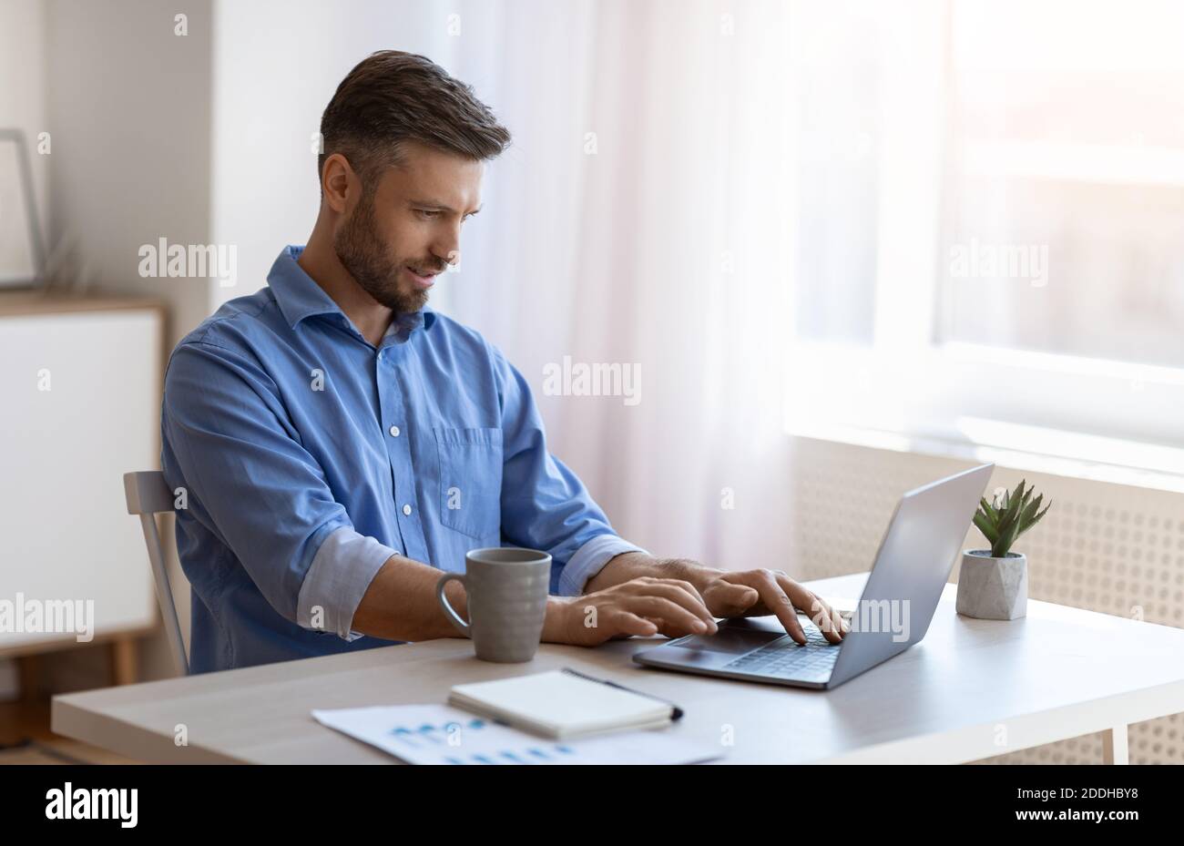 Arbeitsloser Mann Scrolling Job Suche Website zu Hause mit Laptop Computer Stockfoto