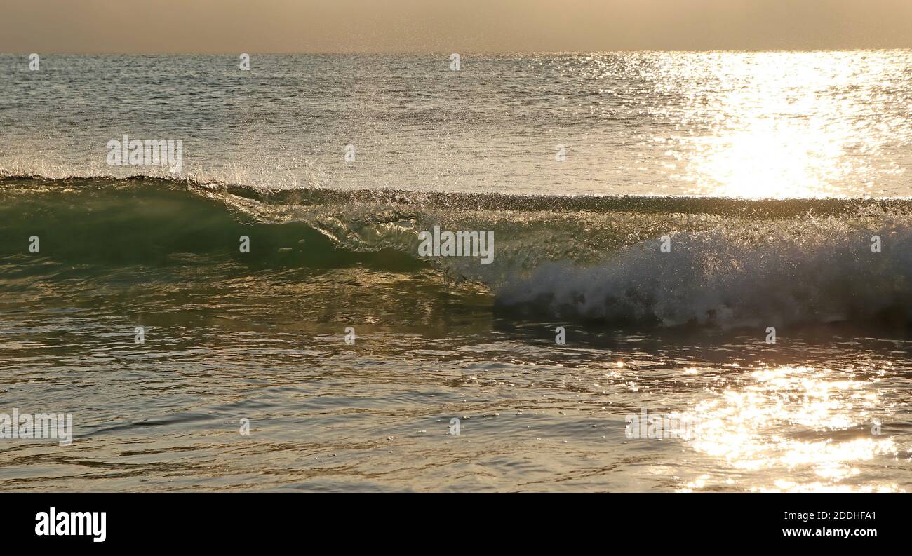 Wellen, die zum Strand gehen, wenn das Sonnenlicht auf den eintrifft Wasser Stockfoto