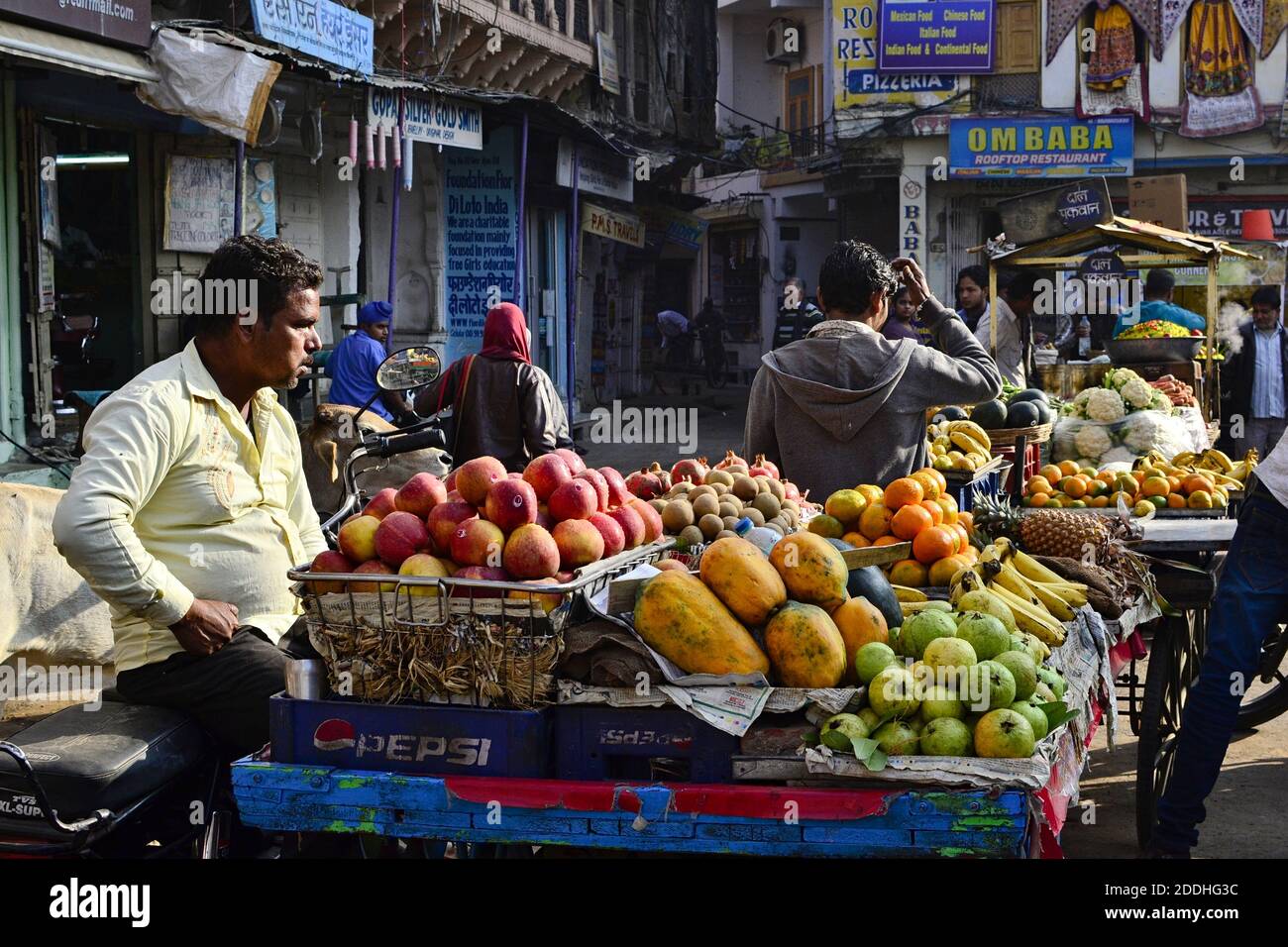 Pushkar, Rajasthan, Indien - Dezember 2016: Indischer Verkäufer, der tropische Früchte (Papaya, Äpfel, Guava, Orangen) vom Verkaufsstand auf der Straße verkauft Stockfoto