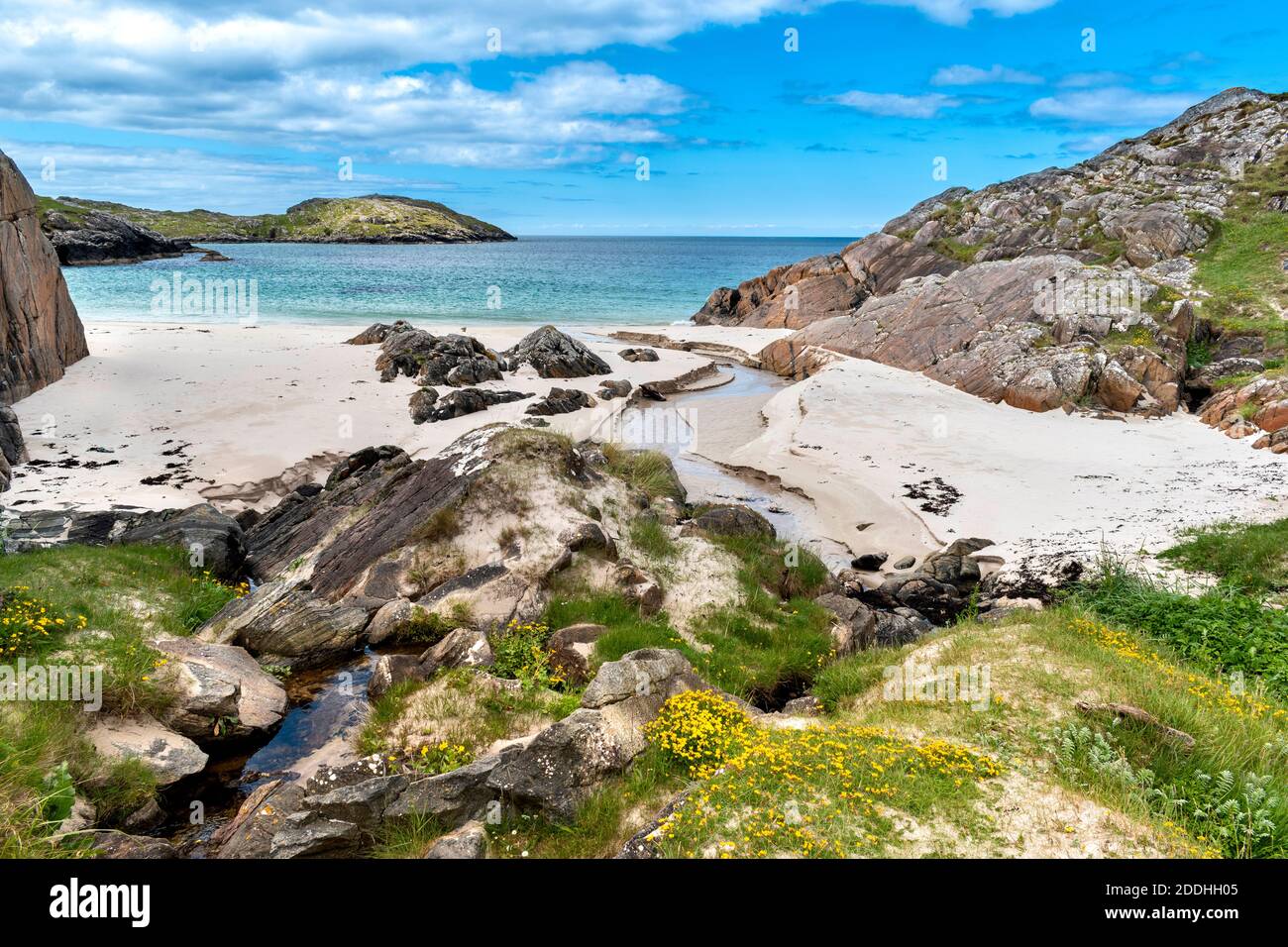ACHMELVICH BAY LOCHINVER SUTHERLAND SCHOTTLAND KLEINER SANDSTRAND EIN KLARER BLAUES UND TÜRKISFARBENES MEER UND SÜSSWASSERBACH Stockfoto