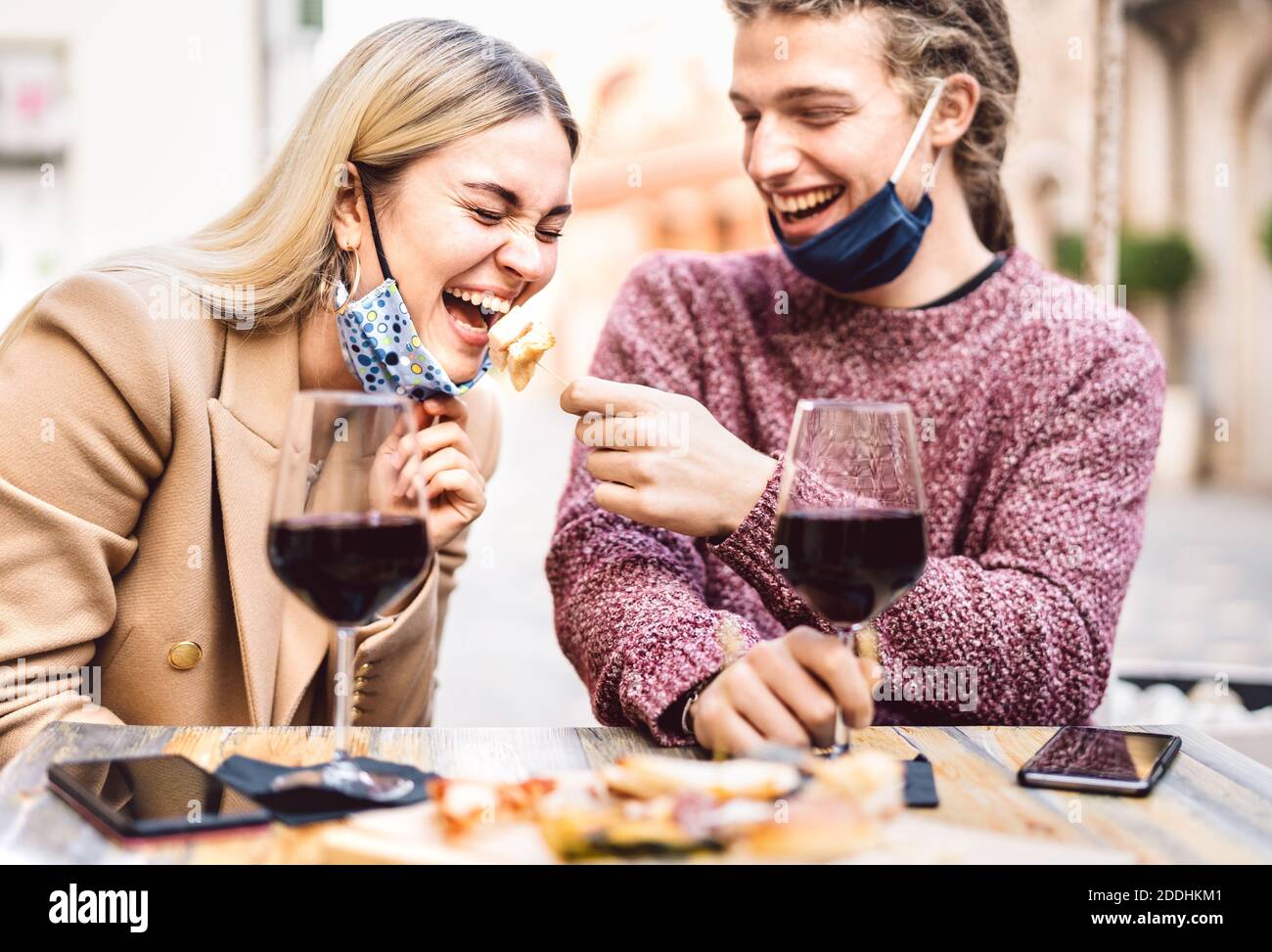 Junges Paar in der Liebe tragen offene Gesichtsmasken Spaß haben In der Weinbar im Freien - Glückliche Reisende Freunde genießen Mittagessen Gemeinsam im Restaurant Garten Stockfoto