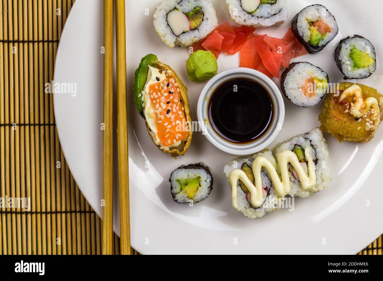 Sushi-Platte mit verschiedenen Sushi-Rollen mit Essstäbchen, Ingwer und Wasabi - Draufsicht mit Platz zum Kopieren Stockfoto