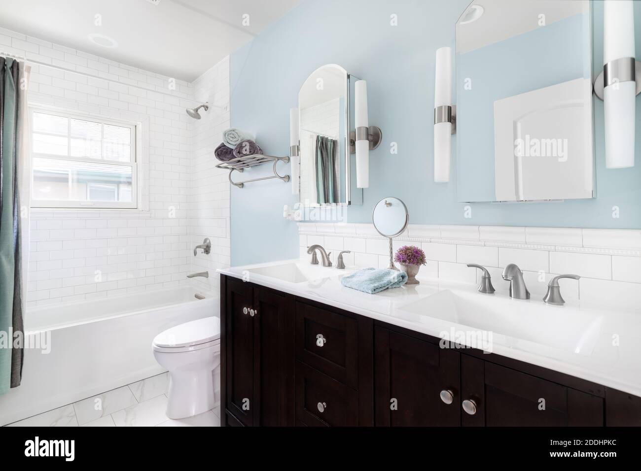 Ein luxuriöses Badezimmer mit dunklem Holzwaschtisch, weißer Granitplatte und blauen Wänden. Stockfoto