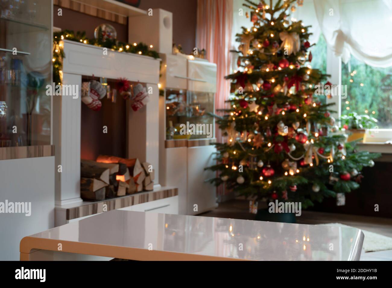 Vorlage von festlich dekorierten Wohnzimmer zu Weihnachten. Kamin und Weihnachtsbaum sind aus dem Fokus. Im Vordergrund befindet sich eine leere weiße Tabelle Stockfoto