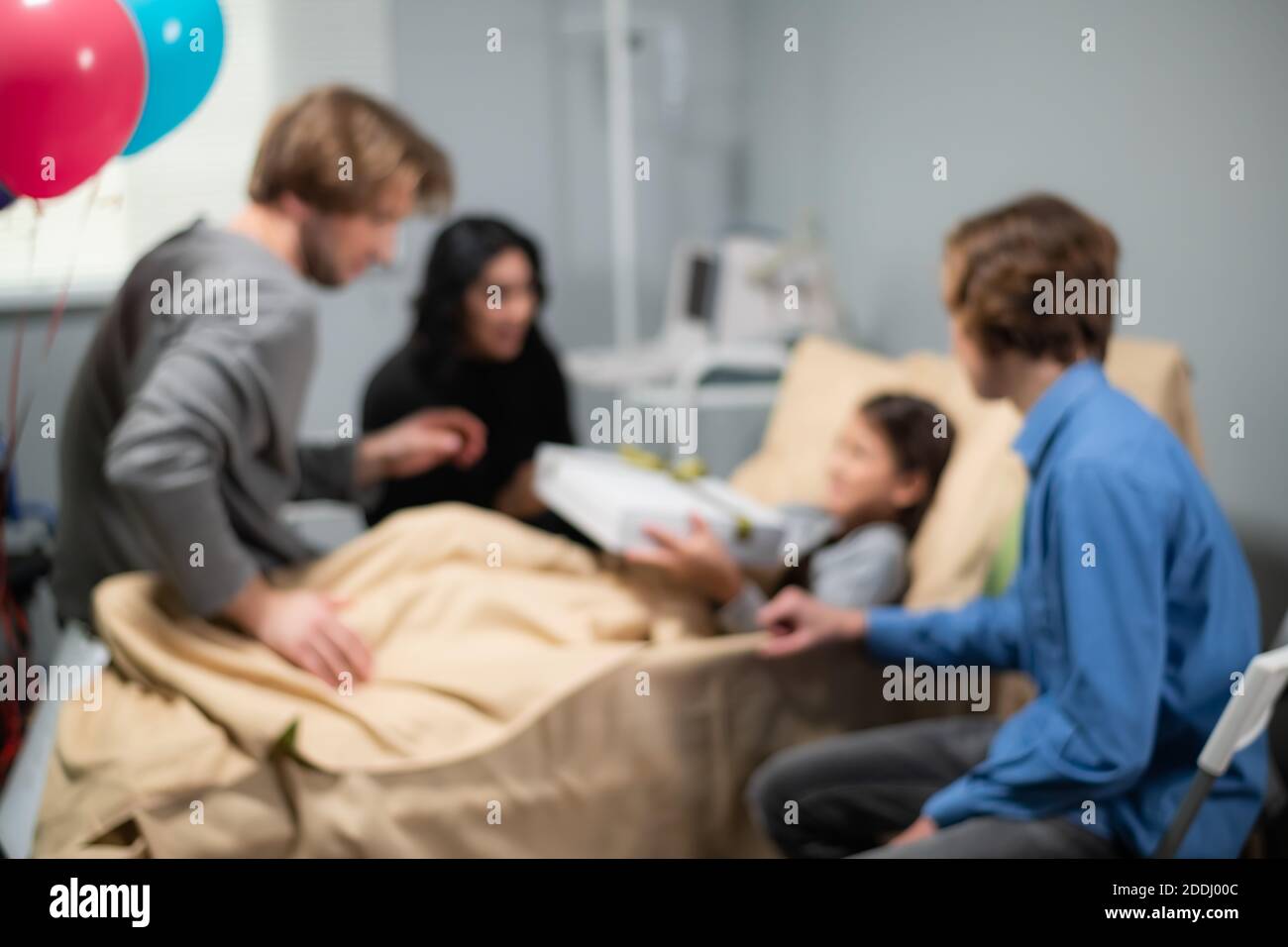 Eine verschwommene Aufnahme einer Familie, die ein Geburtstagskind in einem Krankenhaus besucht. Stockfoto