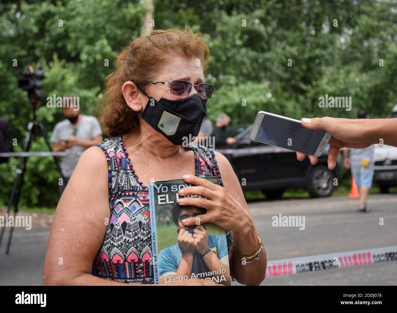 Buenos Aires, Argentinien. November 2020. Eine Frau, die ein Buch mit dem Titel "Ich bin Diego" hält, weint, während sie von einem Journalisten vor dem Haus interviewt wird, in dem Diego Maradona starb. Die argentinische Fußballlegende starb im Alter von 60 Jahren. Kredit: Julieta Ferrario/dpa/Alamy Live Nachrichten Stockfoto