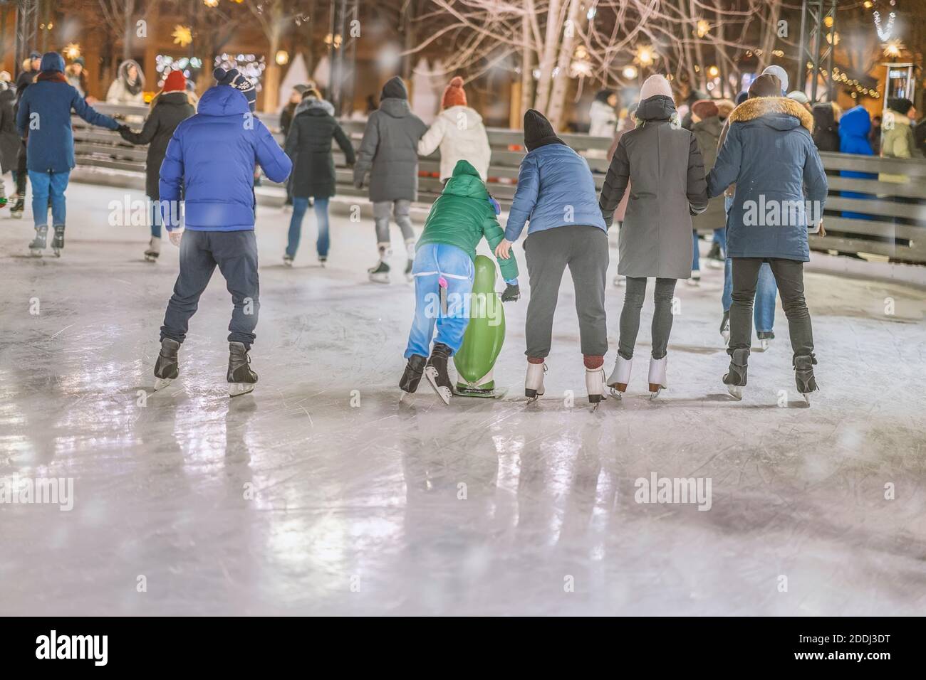 Weihnachten, Winter und Freizeit, Sportkonzept, glückliche Freunde und Familien auf der Eisbahn, Abend im Freien, Feiertagsbeleuchtung Stockfoto