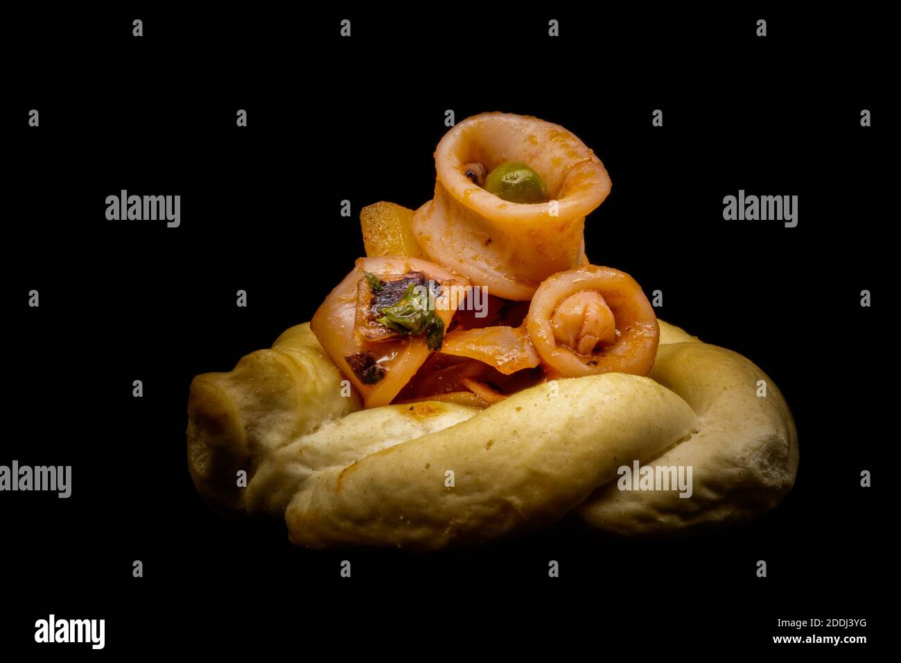 Geschmorte Calamari mit Erbsen, Kartoffeln, Zwiebeln, Petersilie, Tomaten, Pfeffer, Salz, Öl und Zitronenschale auf knusprigem Brot. Stockfoto