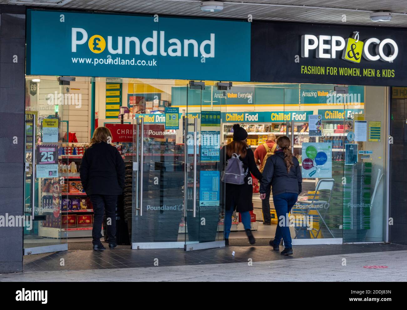 Einkäufer, die eine Filiale der poundland-Shop-Einzelhandelskette mit einem großen poundland-Banner betreten. Stockfoto