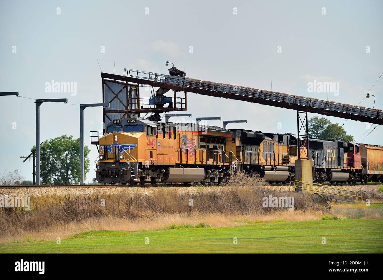 Pesotum, Illinois, USA. Ein Güterzug der Union Pacific in nördlicher Richtung, der an einem Getreideaufzug und einer landwirtschaftlichen Genossenschaft vorbeifährt. Stockfoto