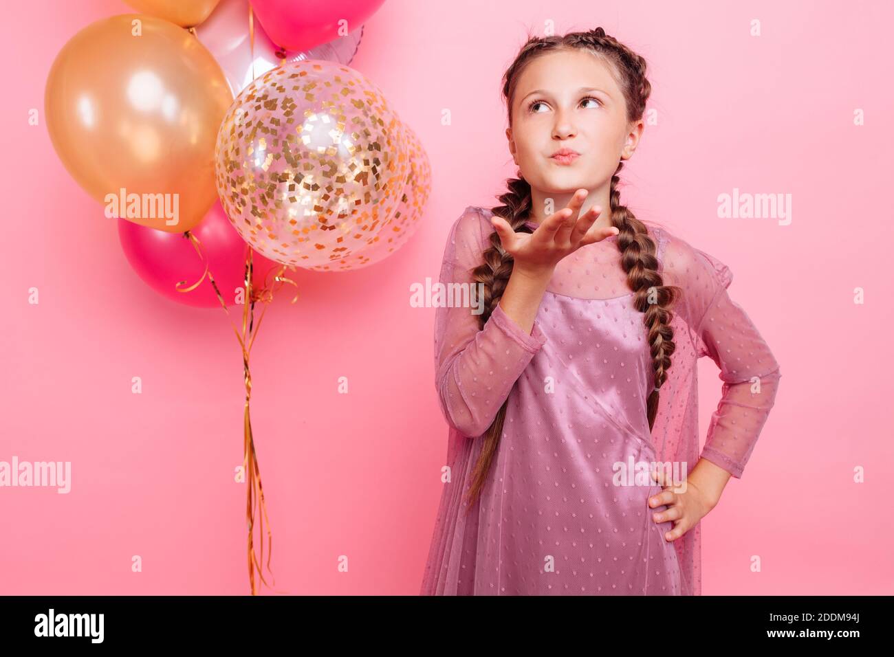 Teenager Mädchen mit Ballons bläst einen Kuss auf die Kamera, auf einem rosa Hintergrund. Party-Konzept Stockfoto