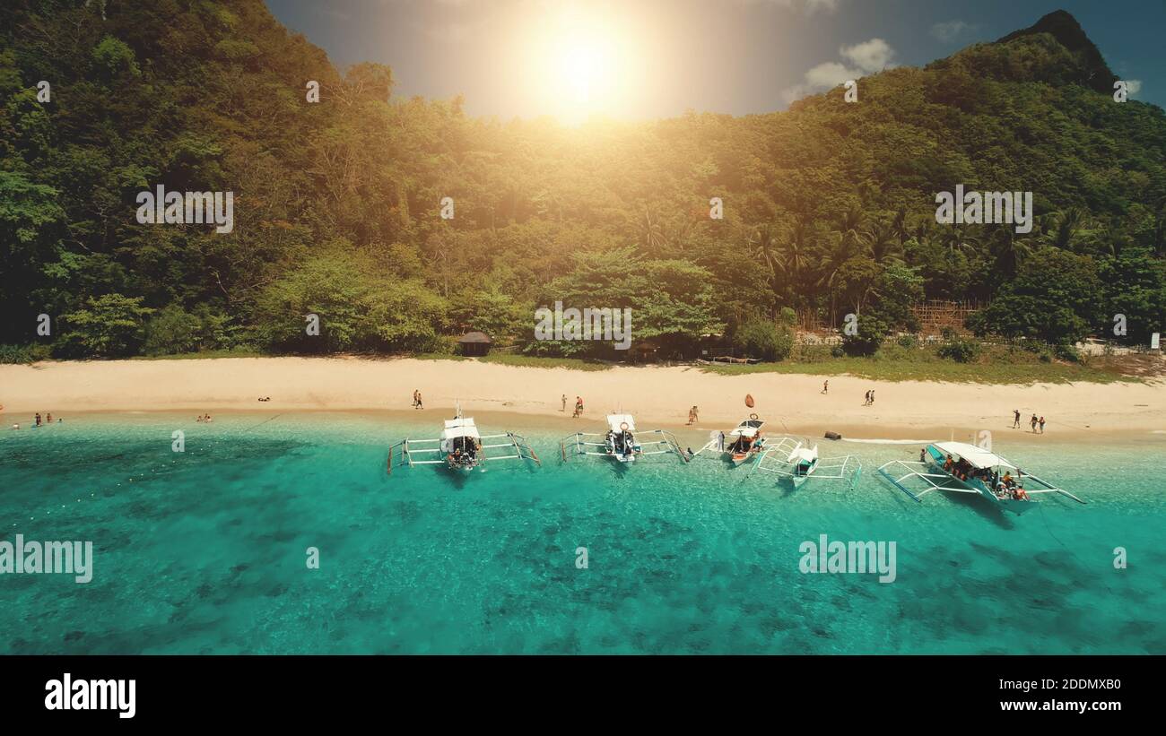 Nahaufnahme Passagierboot in Ocean Bay mit grünen felsigen Ufer bei Sommer Sonne Tag Kreuzfahrt. Tropische Meereslandschaft auf der Berginsel El Nido, Philippinen, Visayas Archipel. Nahaufnahme einer Drohne in Kinoqualität Stockfoto