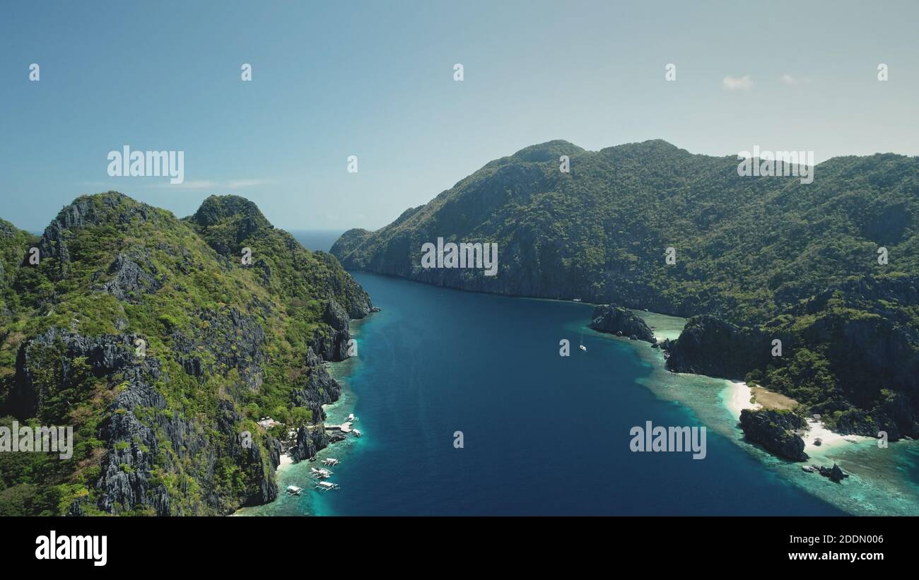 Luftaufnahme von Gebirgsinseln mit Booten und Yachten an der Küste der Meeresbucht. Grüne Bäume auf Felsen und Felsen in sonniger Sommerlandschaft. Sandstrand, wilde Naturlandschaft bei Kreuzfahrt-Tour auf den Philippinen Stockfoto