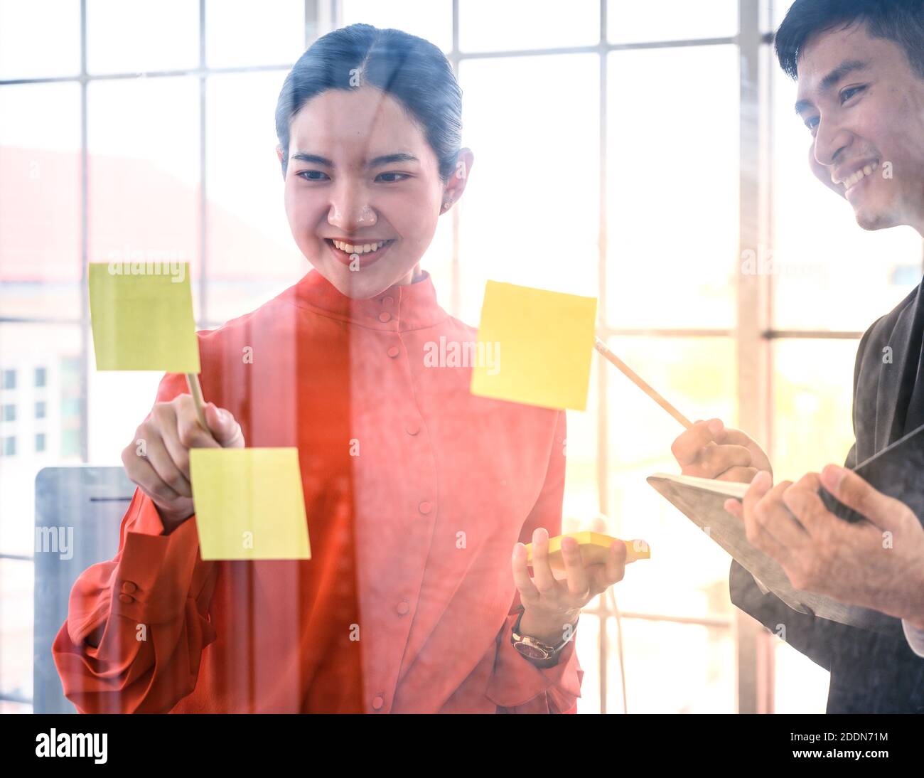 Geschäftspaar trifft sich im Büro und nutzt Post-IT-Notizen, um Ideen auszutauschen. Konzept der geschäftlichen Teamarbeit. Stockfoto