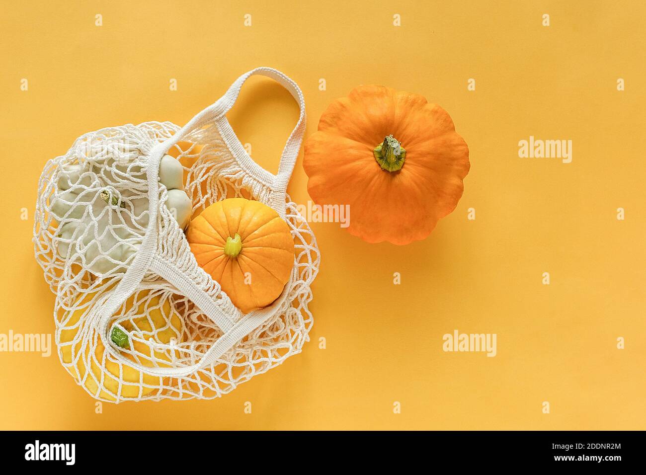 Frische Ernte Gemüse Kürbis Kürbis, Pattypan Squash im Einkaufen umweltfreundliche Netztasche auf gelbem Hintergrund. Konzept Bio-Gemüseernte. Bis Stockfoto