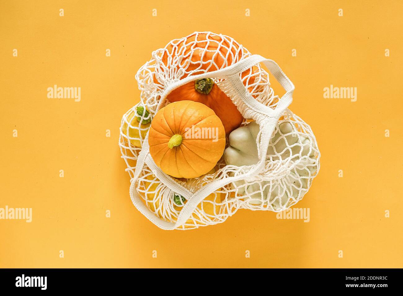 Frische Ernte Gemüse Kürbis Kürbis, Pattypan Squash im Einkaufen umweltfreundliche Netztasche auf gelbem Hintergrund. Konzept Bio-Gemüseernte. Bis Stockfoto