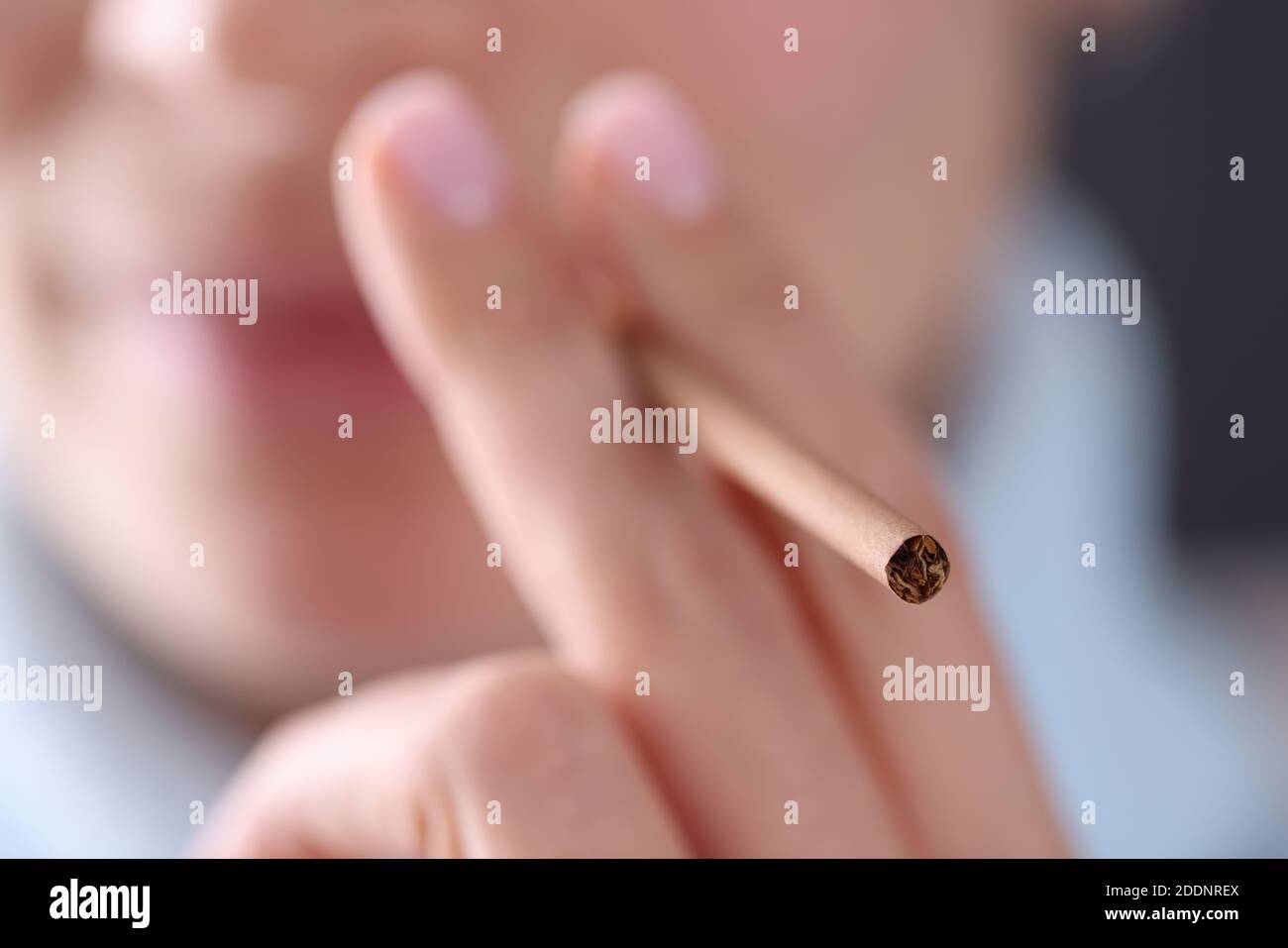 Frau hält Zigarette in der Hand nahe ihrem Mund Nahaufnahme Stockfoto