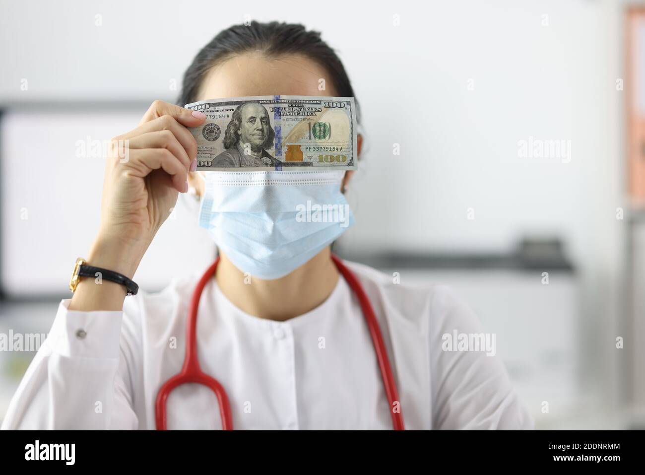 Arzt hält Dollarschein in der Nähe seiner Augen in der Klinik Nahaufnahme Stockfoto