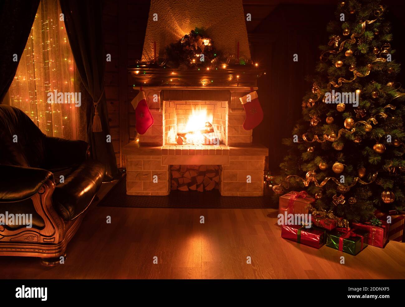 Weihnachtlich geschmückter Baum im dunklen Innenraum mit Kamin, Sessel und Fenster Stockfoto