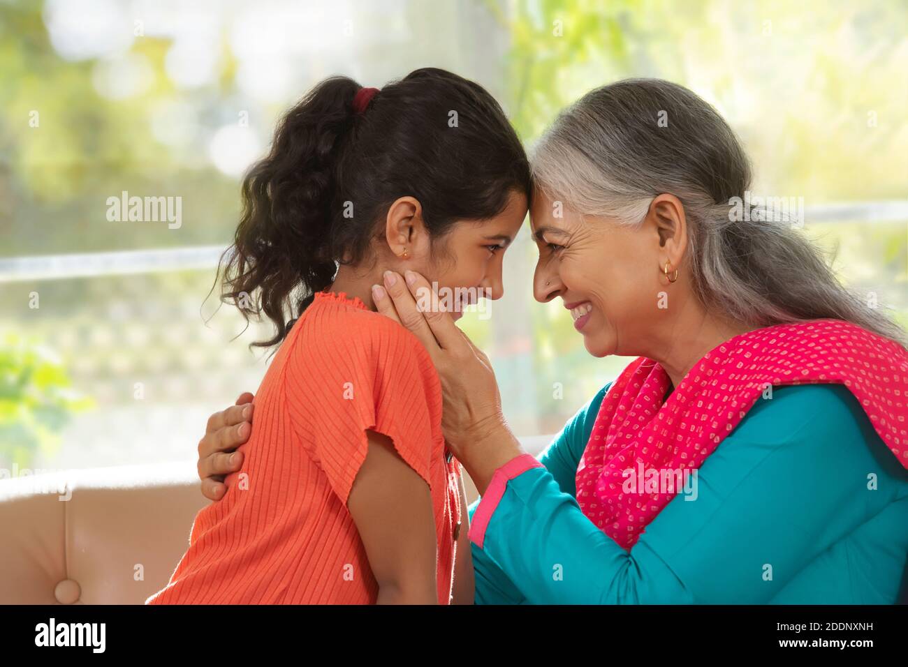 Enkelin und Enkelin berühren die Stirn und zeigen Zuneigung Ein Wohnzimmer Stockfoto