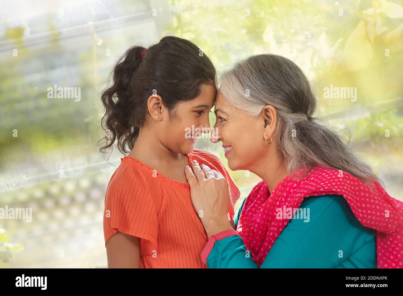 Enkelin und Enkelin berühren die Stirn und zeigen Zuneigung Ein Wohnzimmer Stockfoto
