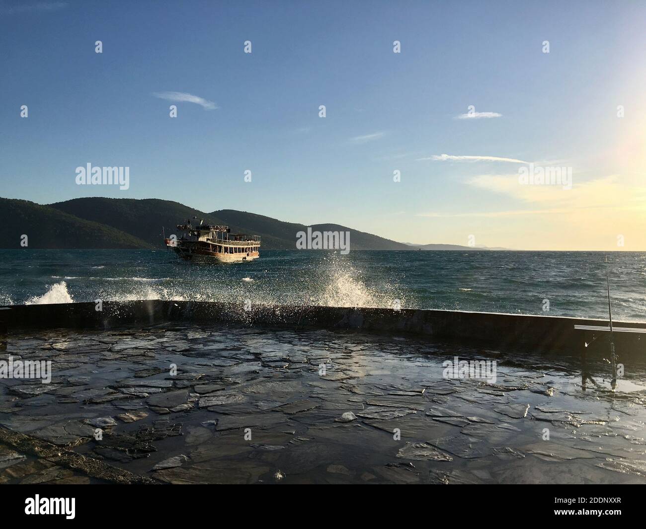 Tour Boot auf Wellenwasser mit nasser Küste. Großer großer Sturm wie Wellen mit offenem klaren blauen Himmel und wenigen Wolken, sonniger Tag. Stockfoto