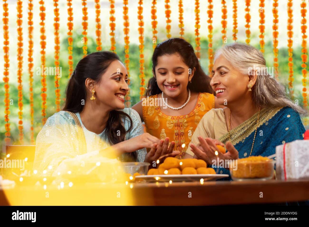 Schwiegermutter Lehre Tochter im Gesetz, wie man macht Ladoo anlässlich Diwali als Enkelin Sieht aus Stockfoto