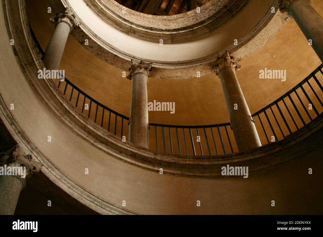 Wendeltreppe mit abgerundeter Rampe. Ins Dunkel, ins Licht. Aufstehen, absenken. Mystische Beleuchtung. Alte historische Mauern und Säulen. Stockfoto