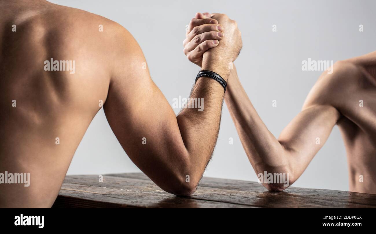 Zwei Männerhände umklammten Arm Wrestling, stark und schwach, ungleiche Übereinstimmung. Armdrücken. Schwer muskulös Mann Arm Wrestling ein mickrigen schwachen Mann. Arme Stockfoto