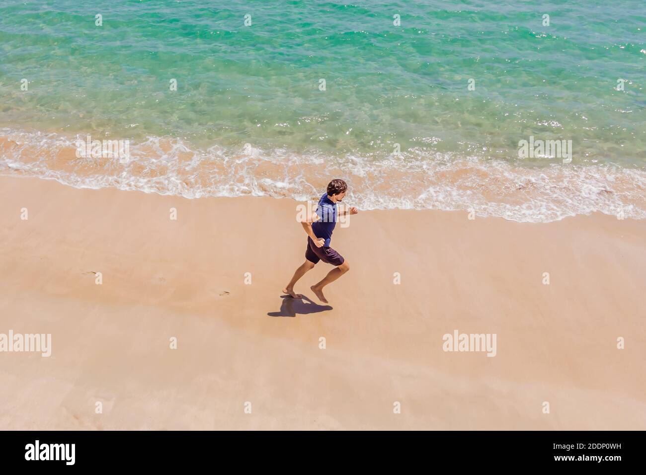 Läufer am Strand am Meer - Blick von oben. Mann Athlet Training Cardio Jogging tun Morgen Training. Hero Luftdrohne Ansicht erschossen, viele Stockfoto
