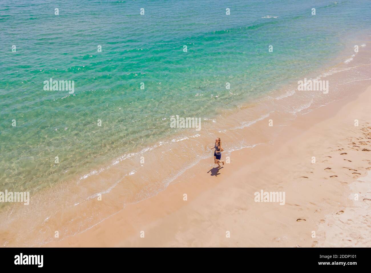 Läufer am Strand am Meer - Blick von oben. Frau Athlet Training Cardio Jogging tun Morgen Workout. Hero Luftdrohne Ansicht erschossen, viele Stockfoto