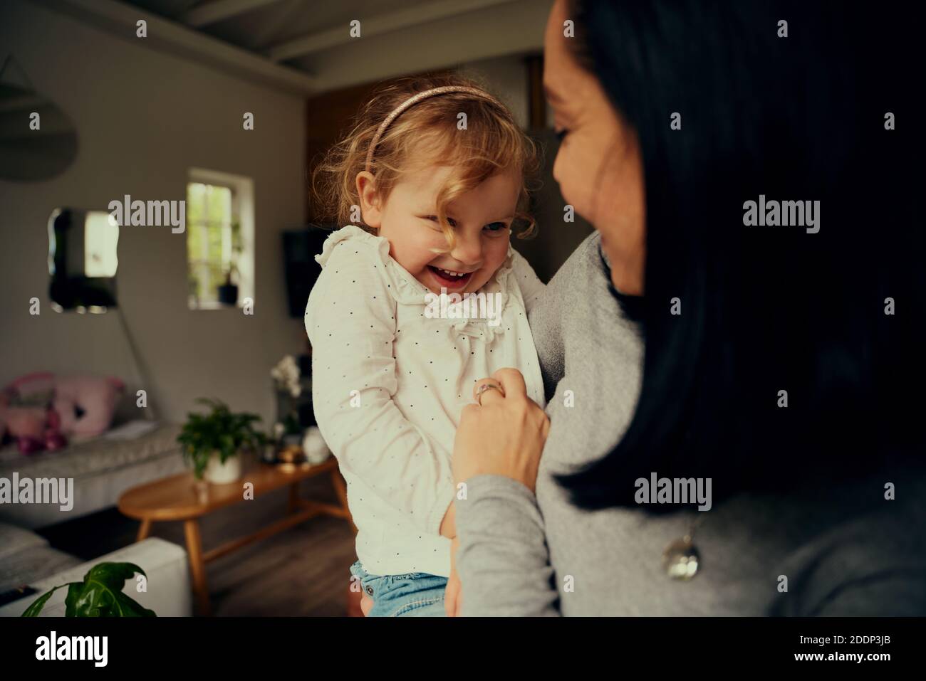 Verspielte Mutter und Tochter kitzeln sich beim Entspannen Zu Hause Stockfoto