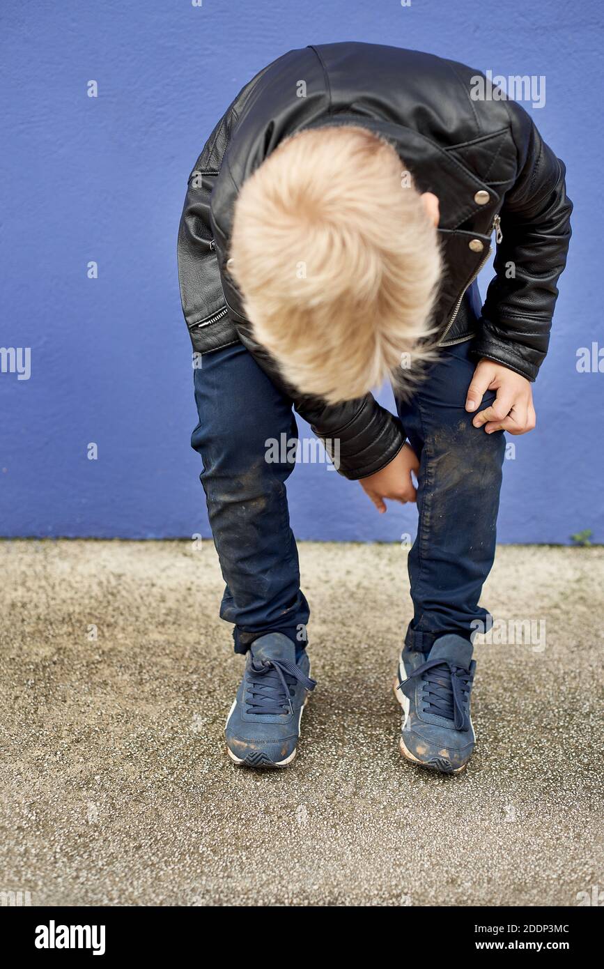 Kind, das nach dem Herunterfallen seine schmutzige Hose anschaut Stockfoto