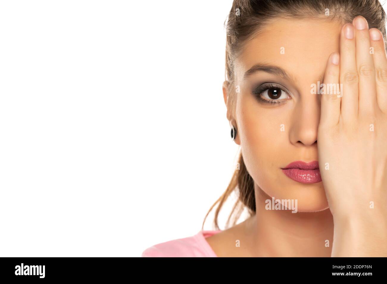 XaPorträt der jungen schönen Frau mit Make-up, bedeckt ihr Auge mit der Hand auf weißem Hintergrund Stockfoto