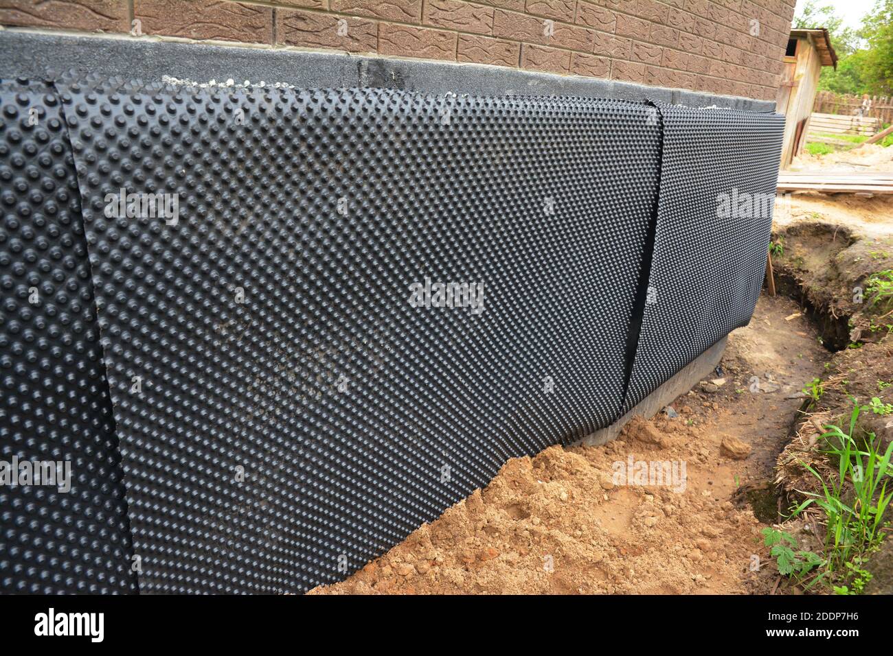 Installation von Imprägnierung gedippte Membran zu isolieren außen Keller oder Fundament Wand eines Ziegelhauses gegen Feuchtigkeit und Wasserlecks. Stockfoto