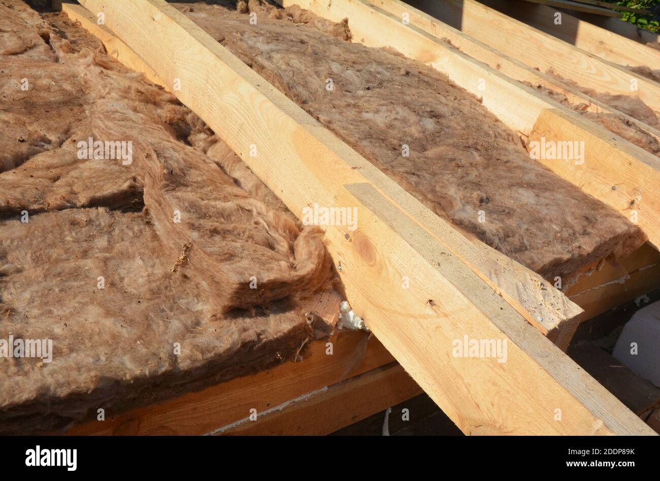 Eine Nahaufnahme auf einem Außendach, Dachboden oder Dachboden Isolierung mit Glas Mineralwolle zwischen den Holzsparren während Schrägdachkonstruktion. Stockfoto