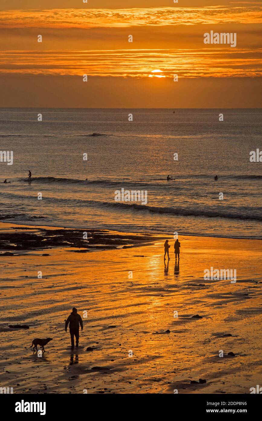 Swansea, Großbritannien. November 2020. Leute gehen am Strand spazieren, während die Sonne über Langland Bay in der Nähe von Swansea an einem kalten und frostigen Herbstmorgen aufgeht. Quelle: Phil Rees/Alamy Live News Stockfoto