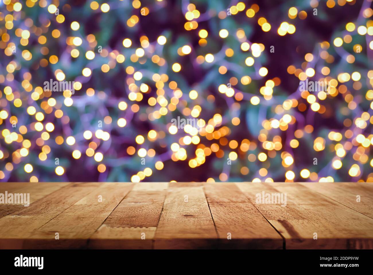Holztischplatte mit Bokeh aus dekorativem Licht an Weihnachten Baum in der Nacht im Hintergrund - kann verwendet werden Zeigen Sie Ihre Produkte an oder stellen Sie sie zusammen Stockfoto