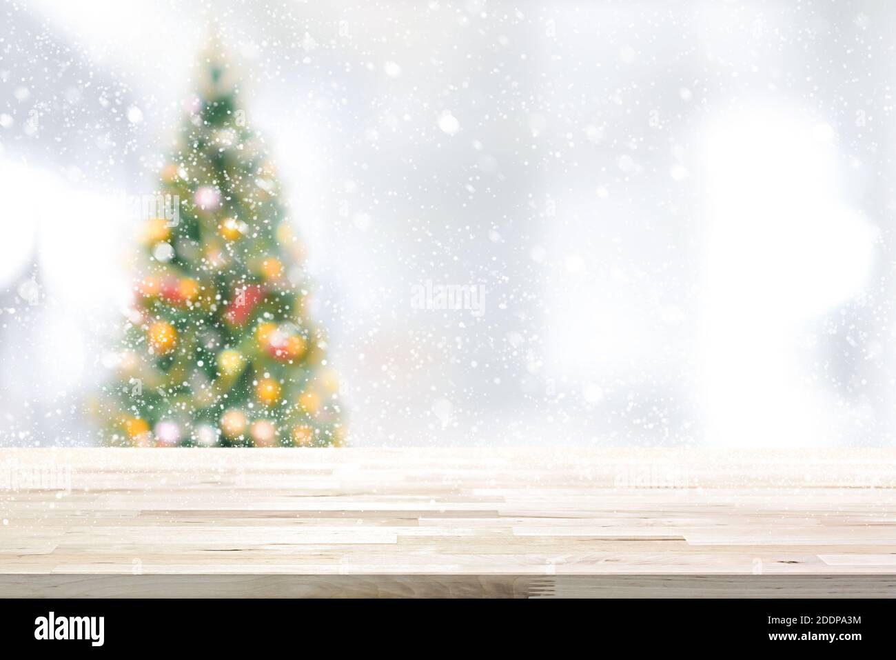 Holz Tischplatte auf Blur Weihnachtsbaum im Schneefall Hintergrund Stockfoto
