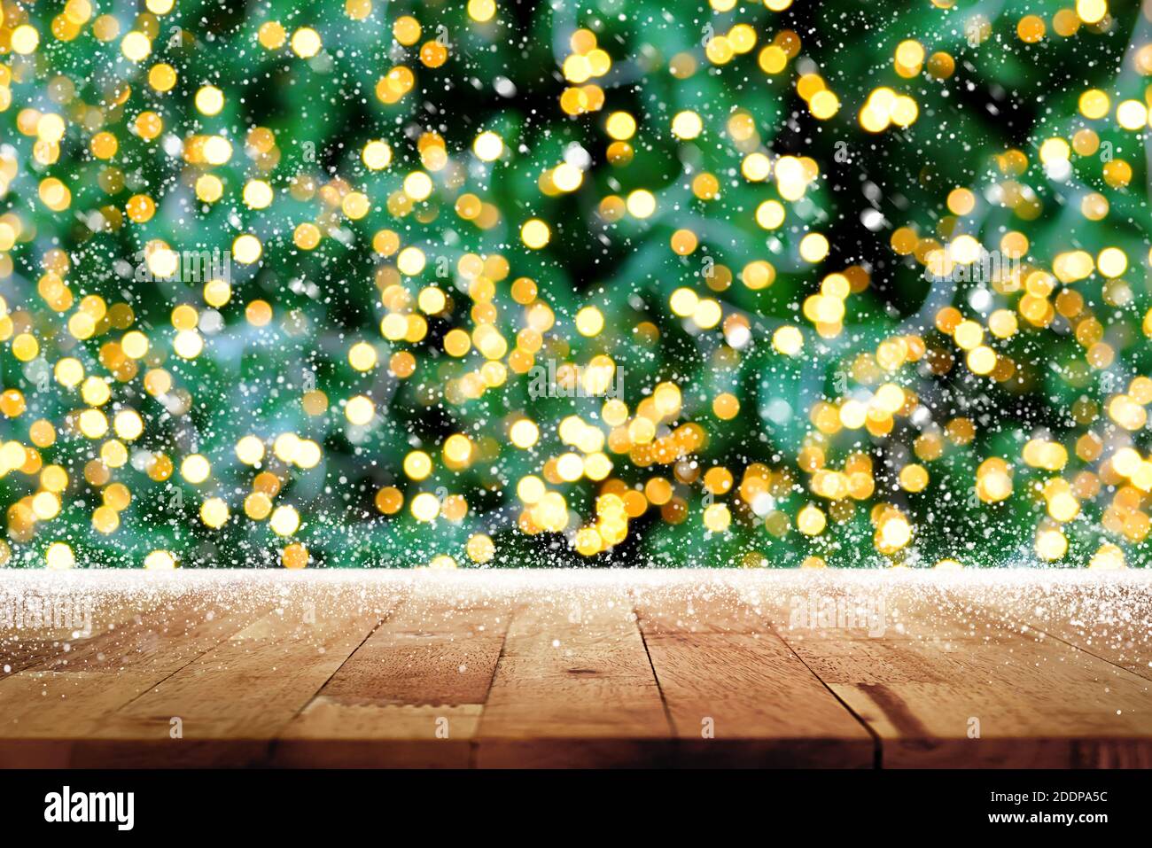 Holztischplatte mit Bokeh aus dekorativem Licht an weihnachten Baum und Schnee im Hintergrund Stockfoto