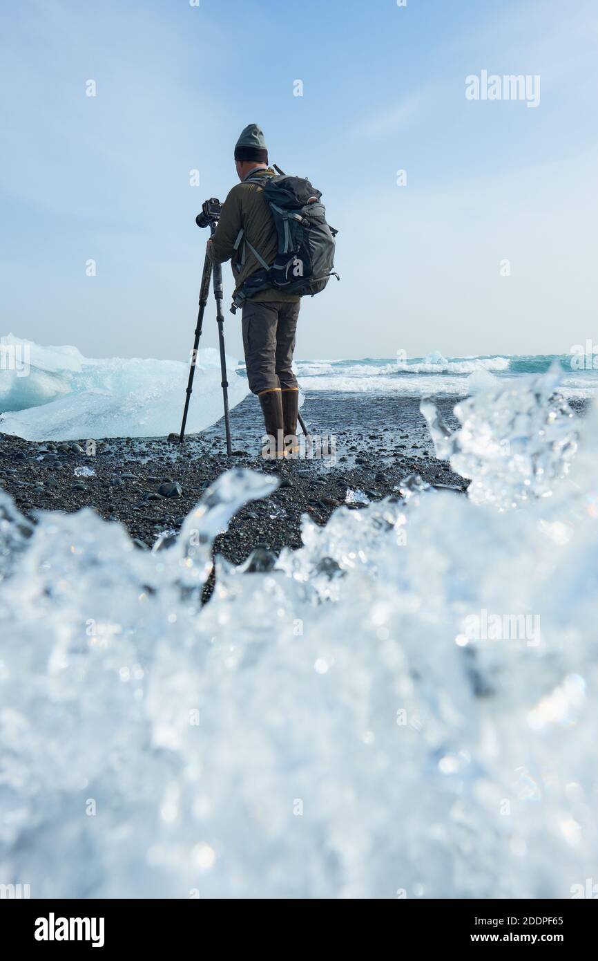 Ein Tourist auf der beliebten schwarzen Sandstrand von Jokulsarlon wo Eisberg Fragmente regelmäßig gewaschen und fotografiert. Stockfoto