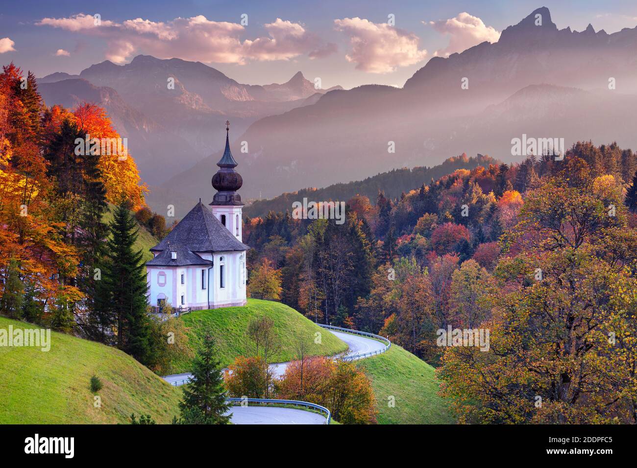 Bayerische Alpen. Landschaftsbild der Bayerischen Alpen mit Maria-Gern-Kirche und Watzmann-Berg bei schönem Herbstuntergang. Stockfoto