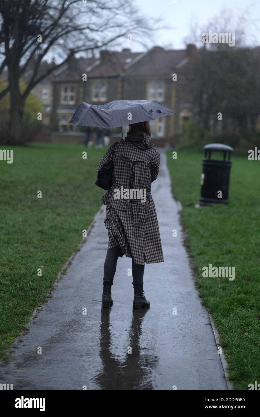 Eine Frau mit Regenschirm an einem regnerischen Tag mit einem kaputten Regenschirm. Stockfoto