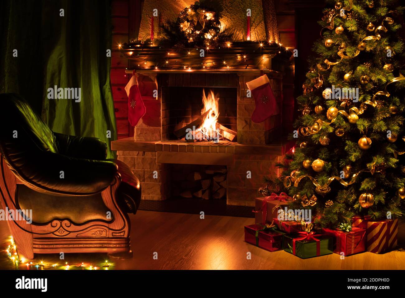Weihnachtlich geschmückter Baum im Innenraum mit Kamin, grünem Sessel und Vorhängen Stockfoto